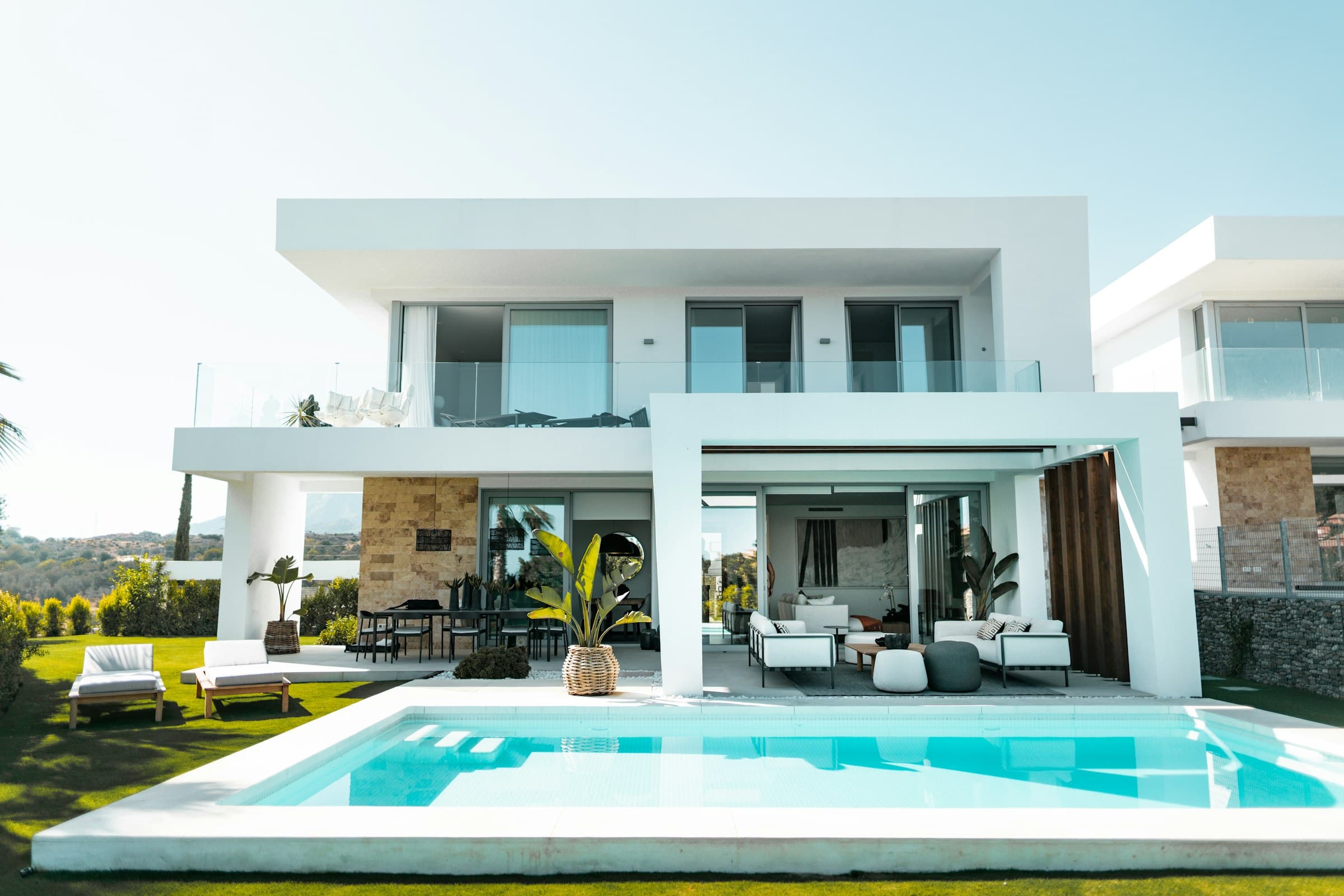 Modern Marbella villa with large sliding glass doors and windows opening onto a pool terrace